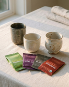 Three ceramic cups on a light surface with organic tea packages in front — Wu Wei Living