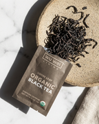 Wu Wei Living organic black tea package with loose leaf tea on a marble surface